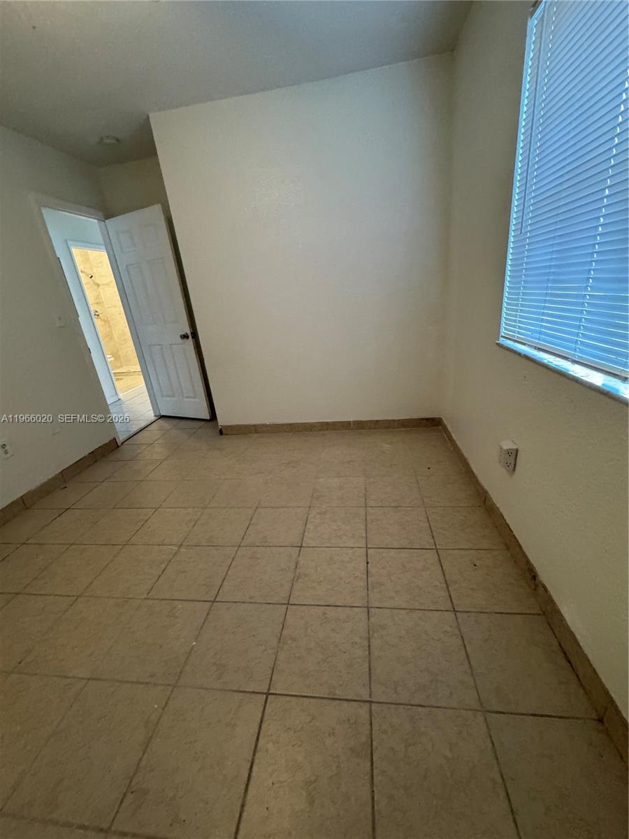 An empty room features beige tile flooring, white walls, and a window with blinds — 20138 NW 38th Pl, Miami Gardens FL 33055, MIAMI GARDENS, FL