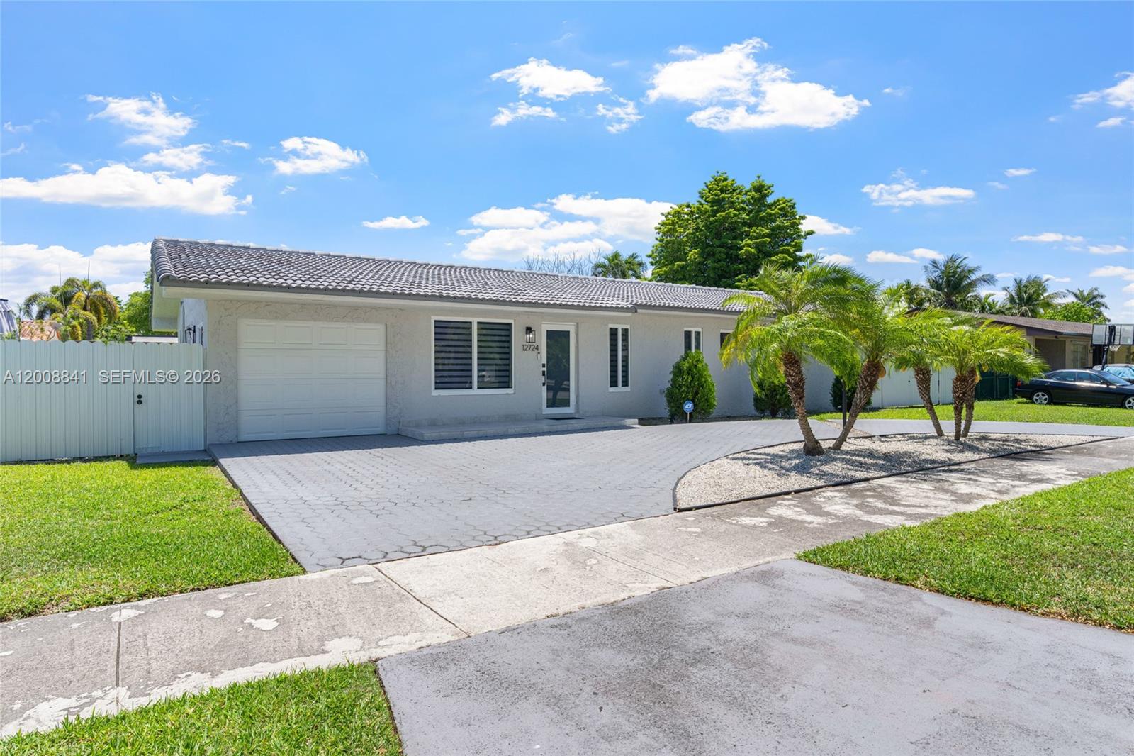 A single-story house with a gray tile roof, paved driveway, and palm trees in front — 12724 SW 33rd Ter, Miami FL 33175, MIAMI, FL