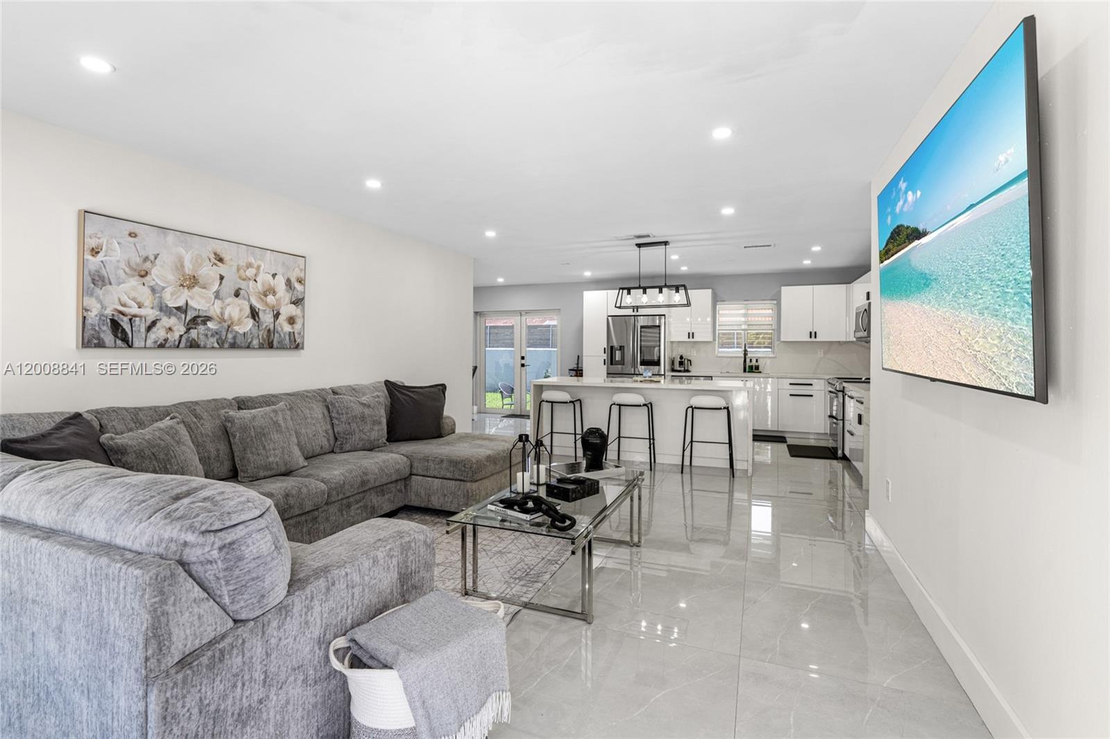 This open-concept living room and kitchen features gray tile flooring and a sectional sofa — 12724 SW 33rd Ter, Miami FL 33175, MIAMI, FL