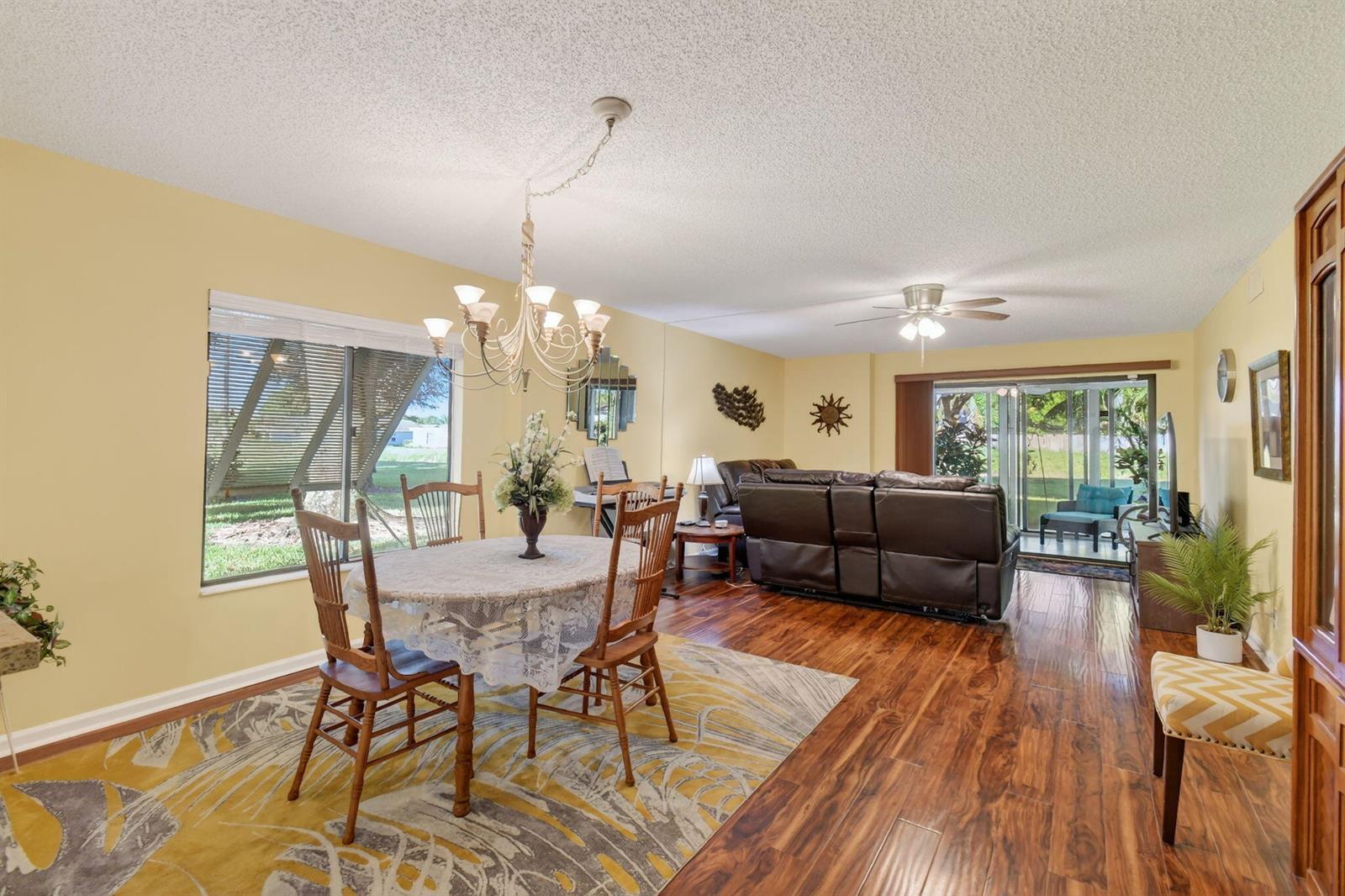 A dining area with a round table and a living room with dark leather furniture — 10155 Mangrove Drive # 101, Boynton Beach FL 33437, BOYNTON BEACH, FL