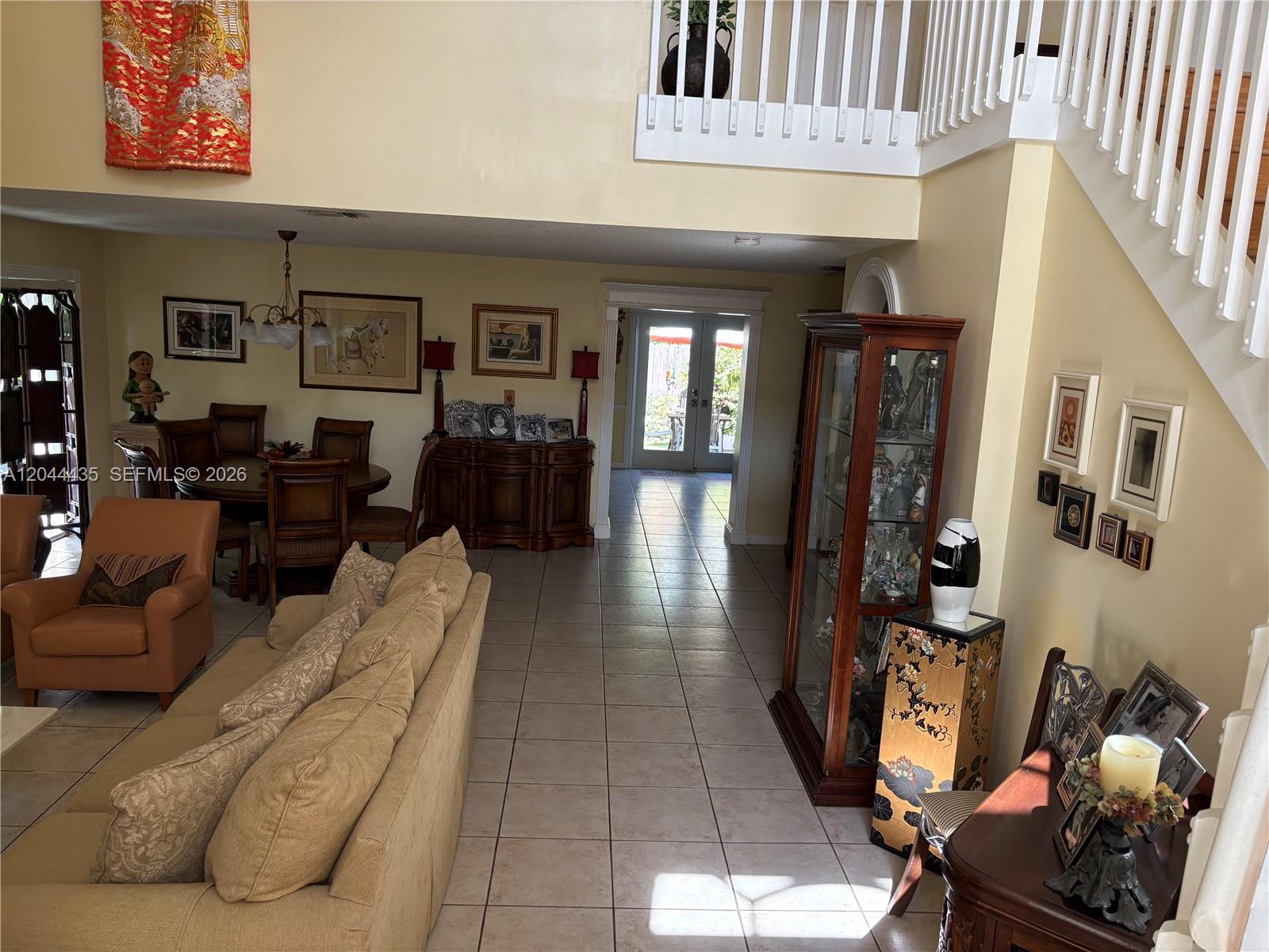 A living room and dining area feature tile floors, a staircase, and a display cabinet — 9217 SW 157th Path, Miami FL 33196, MIAMI, FL