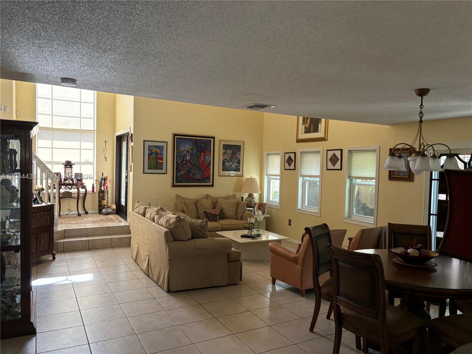 A spacious living and dining area features tile flooring, yellow walls, and a sunken entryway — 9217 SW 157th Path, Miami FL 33196, MIAMI, FL