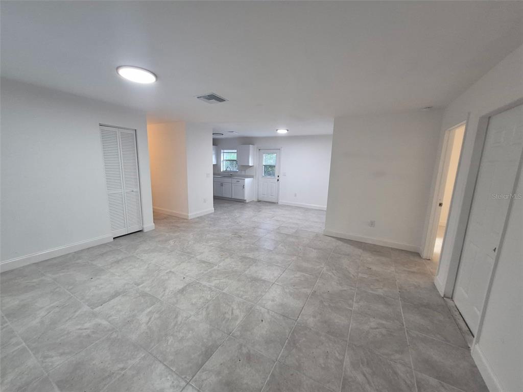 A bright, open-concept living area features light gray tile flooring and white walls — 5907 NW 64TH STREET, OCALA, FL