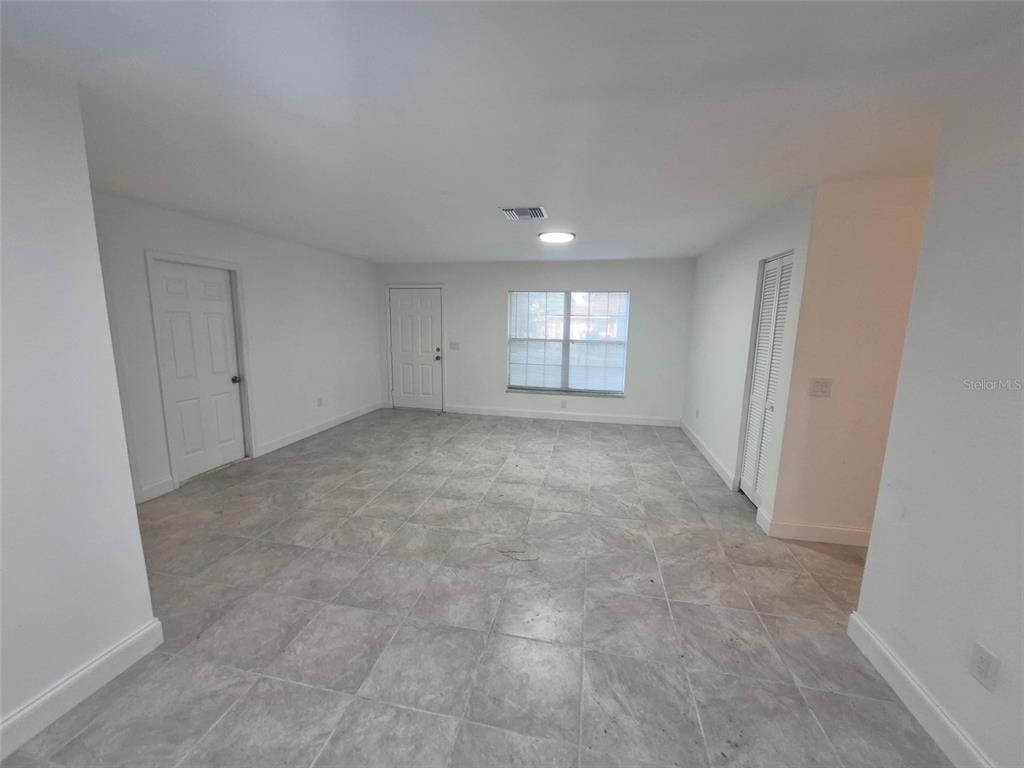 An empty room with white walls, gray tile flooring, a window, and two doors — 5907 NW 64TH STREET, OCALA, FL