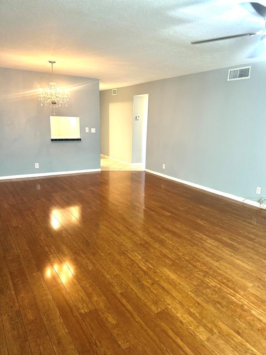 An empty room with light blue walls, hardwood floors, and a crystal chandelier — 2600 NE 1st Lane # 418, Boynton Beach FL 33435, BOYNTON BEACH, FL