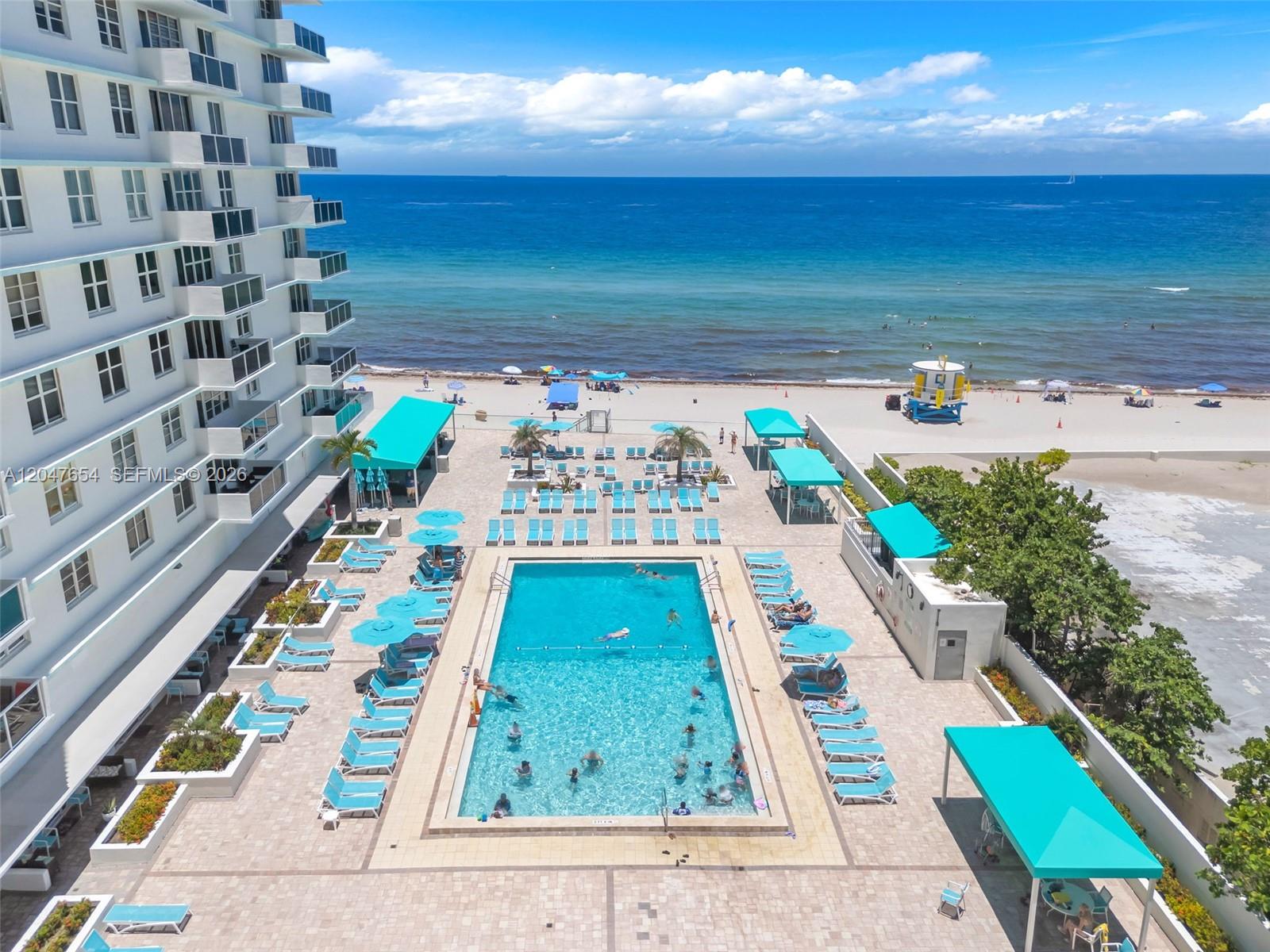 An aerial view shows a swimming pool deck with lounge chairs beside a beach — 3725 S Ocean Dr, Hollywood FL 33019, HOLLYWOOD, FL