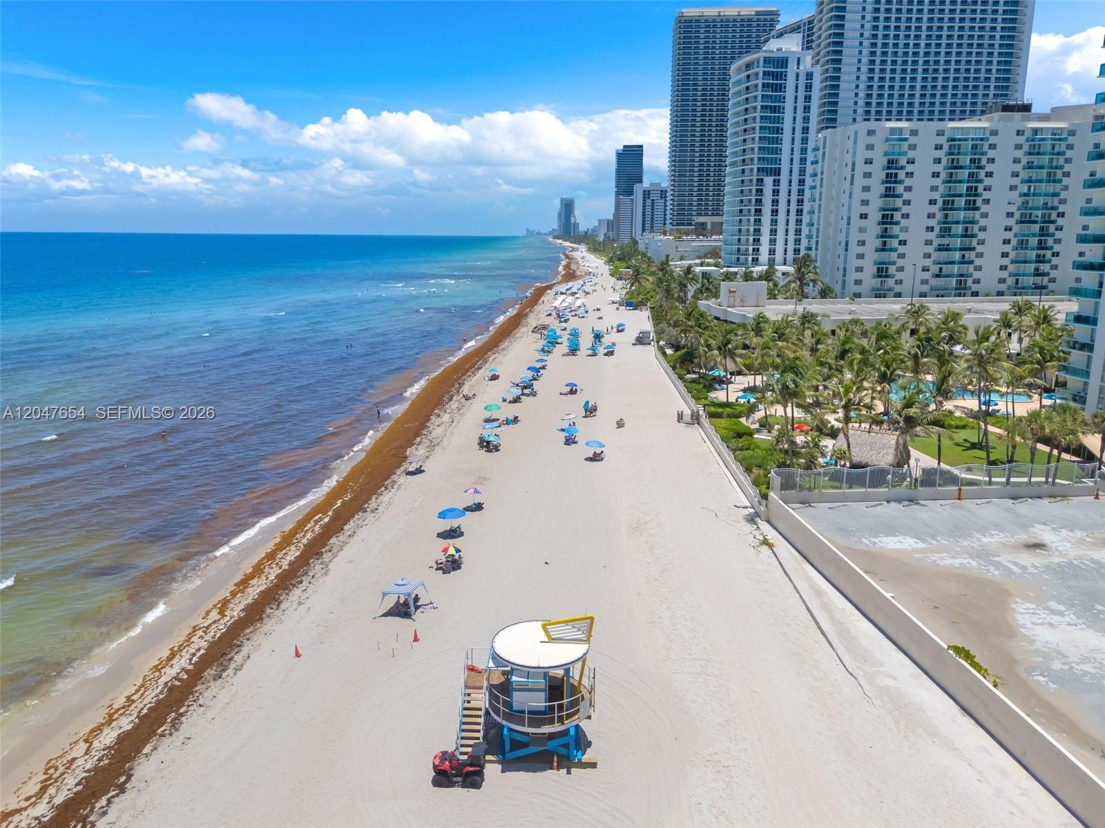 An aerial view shows a sandy beach with a lifeguard tower and high-rise buildings — 3725 S Ocean Dr, Hollywood FL 33019, HOLLYWOOD, FL