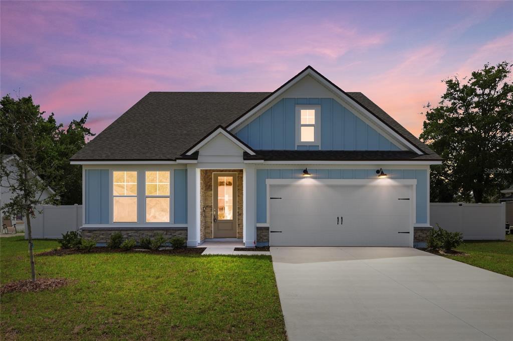 A blue, single-story house with a two-car garage, stone accents, and a concrete driveway — 14 PROSPECT LANE, PALM COAST, FL