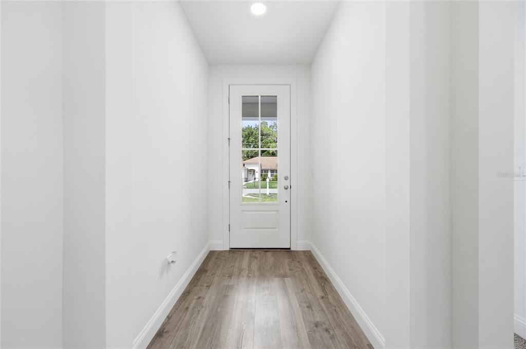 A narrow entryway with white walls, wood-look flooring, and a glass-paneled front door — 14 PROSPECT LANE, PALM COAST, FL
