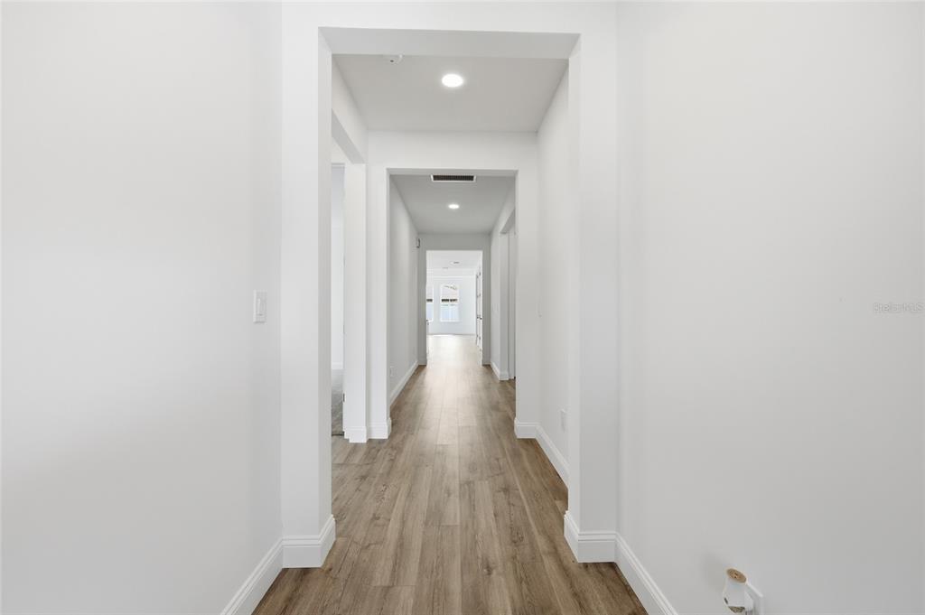 A bright hallway features white walls, wood-look flooring, and recessed lighting — 14 PROSPECT LANE, PALM COAST, FL