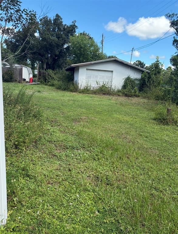 A white detached garage sits at the back of a grassy, overgrown yard — 12486 POEM AVENUE, PUNTA GORDA, FL