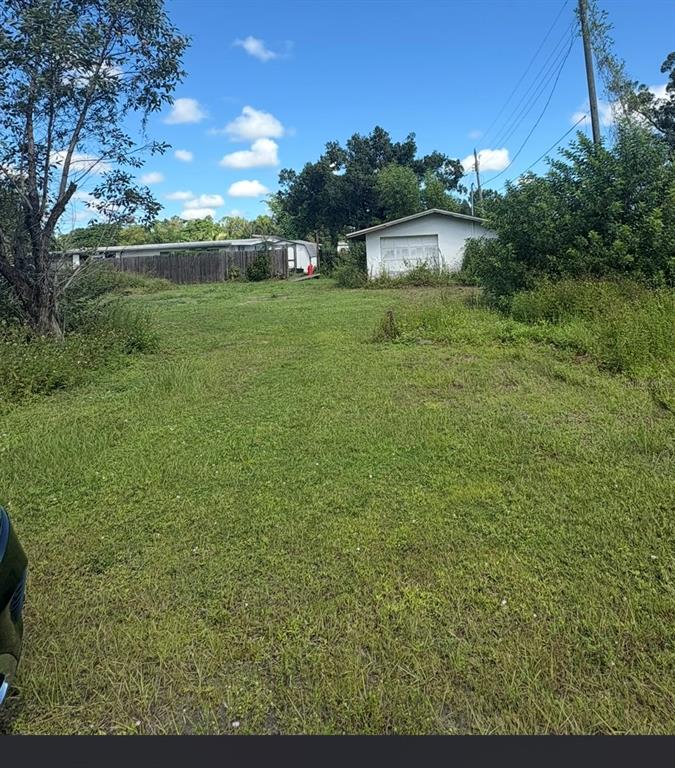 A grassy lot features a detached white garage and a neighboring mobile home with fencing — 12486 POEM AVENUE, PUNTA GORDA, FL