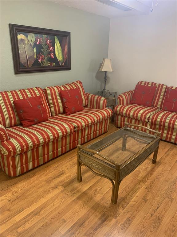 A living room features two striped sofas, a glass-topped rattan coffee table, and wall art — 2777 N POINCIANA BOULEVARD UNIT 225A, KISSIMMEE, FL