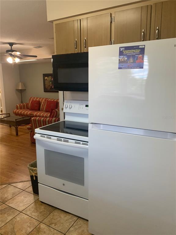 A white refrigerator and stove stand in a kitchen next to a living area — 2777 N POINCIANA BOULEVARD UNIT 225A, KISSIMMEE, FL