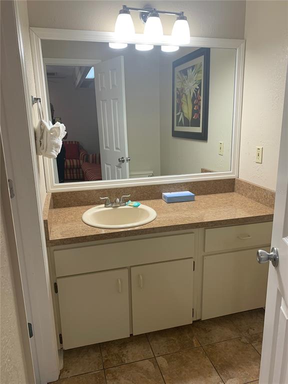 A bathroom vanity features a beige countertop, a single sink, and a large wall mirror — 2777 N POINCIANA BOULEVARD UNIT 225A, KISSIMMEE, FL