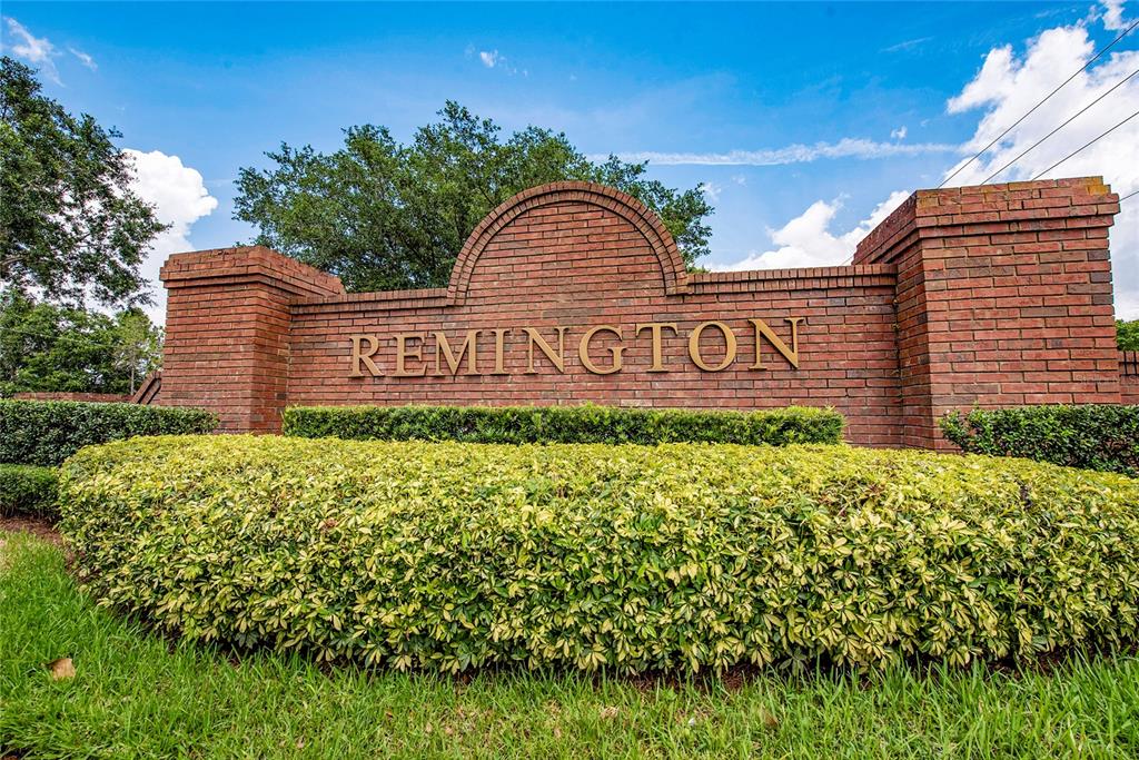 A brick monument sign with the word Remington sits behind a manicured green hedge — 2608 BRANDYWINE COURT, KISSIMMEE, FL