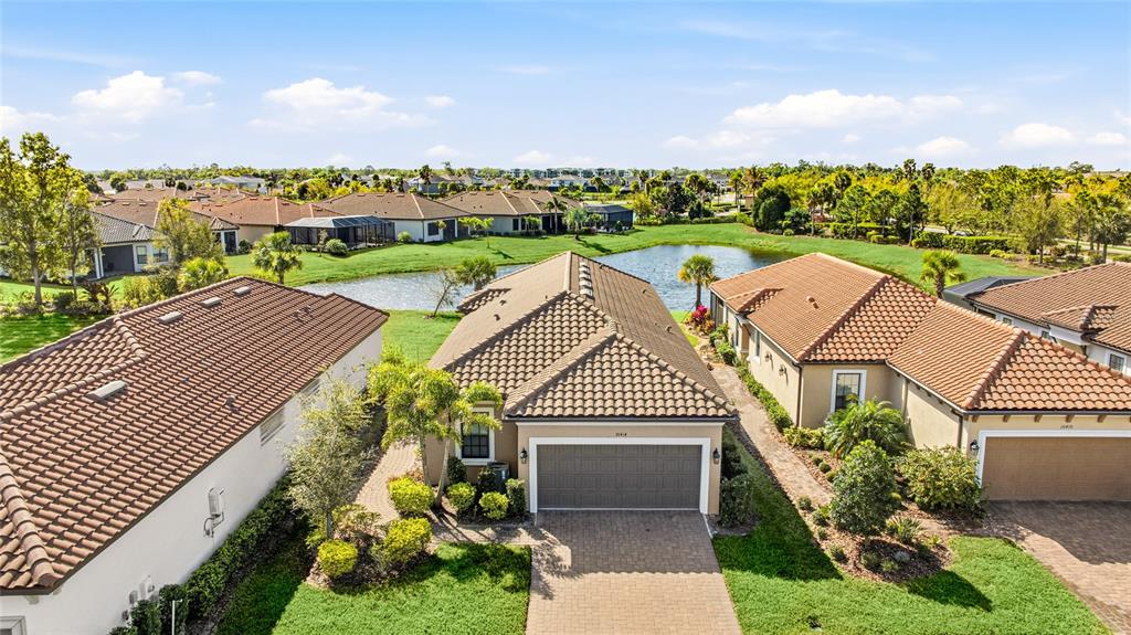 An aerial view shows suburban houses with tile roofs and driveways near a small pond — 10414 INGLENOOK TERRACE, PALMETTO, FL