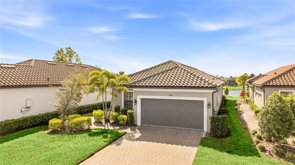 An exterior view of a single-story house with a tiled roof and paved driveway — 10414 INGLENOOK TERRACE, PALMETTO, FL