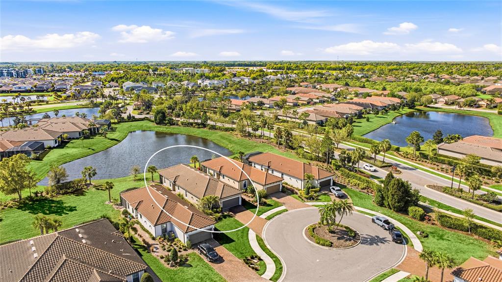 An aerial view shows a residential neighborhood with houses surrounding a central pond — 10414 INGLENOOK TERRACE, PALMETTO, FL