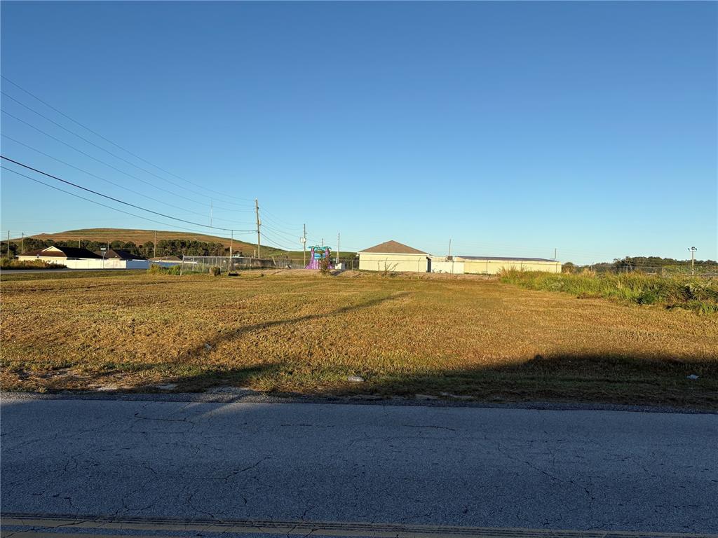 A vacant, grassy lot sits alongside a paved road with buildings in the background — 0 DOGWOOD ROAD, OCALA, FL