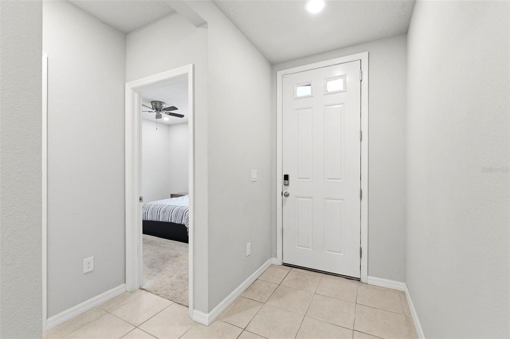 An entryway with light-colored tile flooring, white walls, and a white front door — 38905 HARLOW ROSE DRIVE, ZEPHYRHILLS, FL