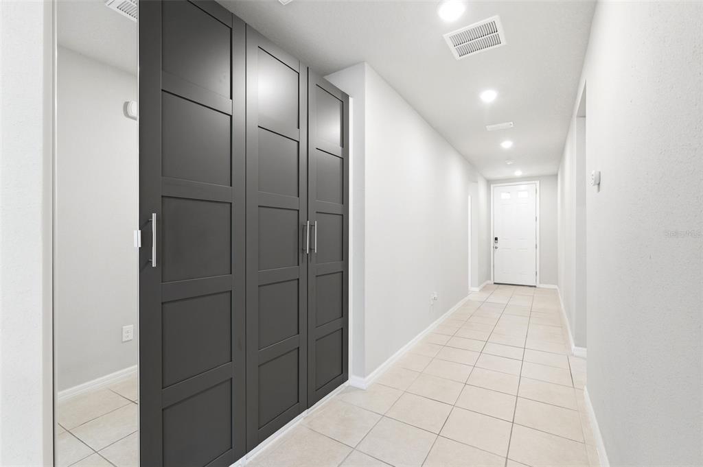 A hallway features light tile flooring, white walls, recessed lighting, and dark gray paneled closet doors — 38905 HARLOW ROSE DRIVE, ZEPHYRHILLS, FL
