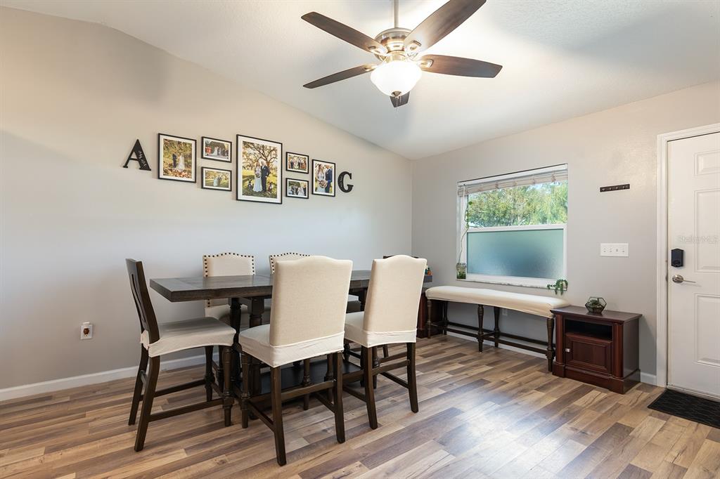 A dining room features a wooden table, upholstered chairs, a ceiling fan, and wood-look flooring — 12146 VIRGINIA DRIVE, LEESBURG, FL