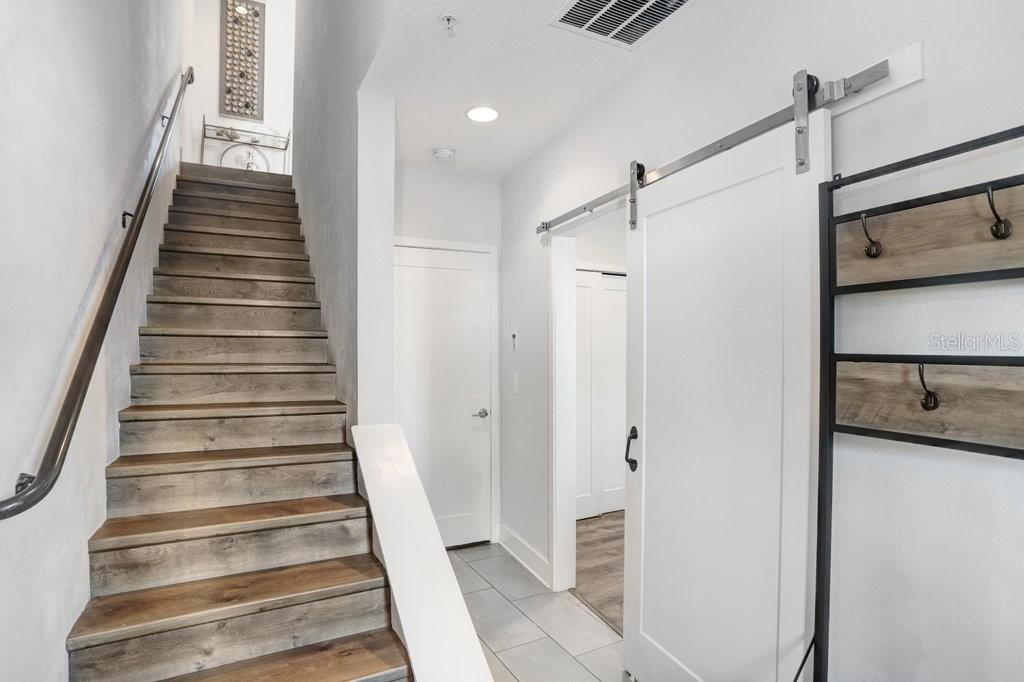 A staircase with wood treads leads upward next to a white sliding barn door — 2511 N GRADY AVENUE UNIT 85, TAMPA, FL