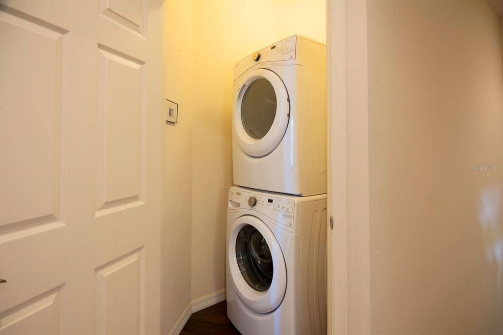 A stacked white washer and dryer set is located in a small laundry closet — 8931 SHINE DRIVE, KISSIMMEE, FL