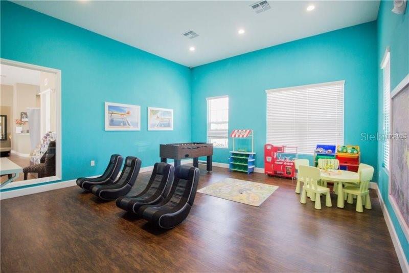 A playroom features turquoise walls, dark wood flooring, gaming chairs, a foosball table, and toys — 8931 SHINE DRIVE, KISSIMMEE, FL