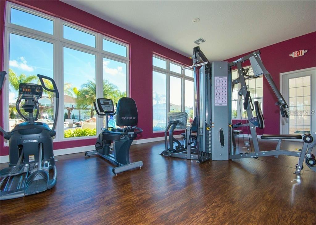 A fitness room with exercise equipment, dark wood flooring, and large windows against purple walls — 8931 SHINE DRIVE, KISSIMMEE, FL