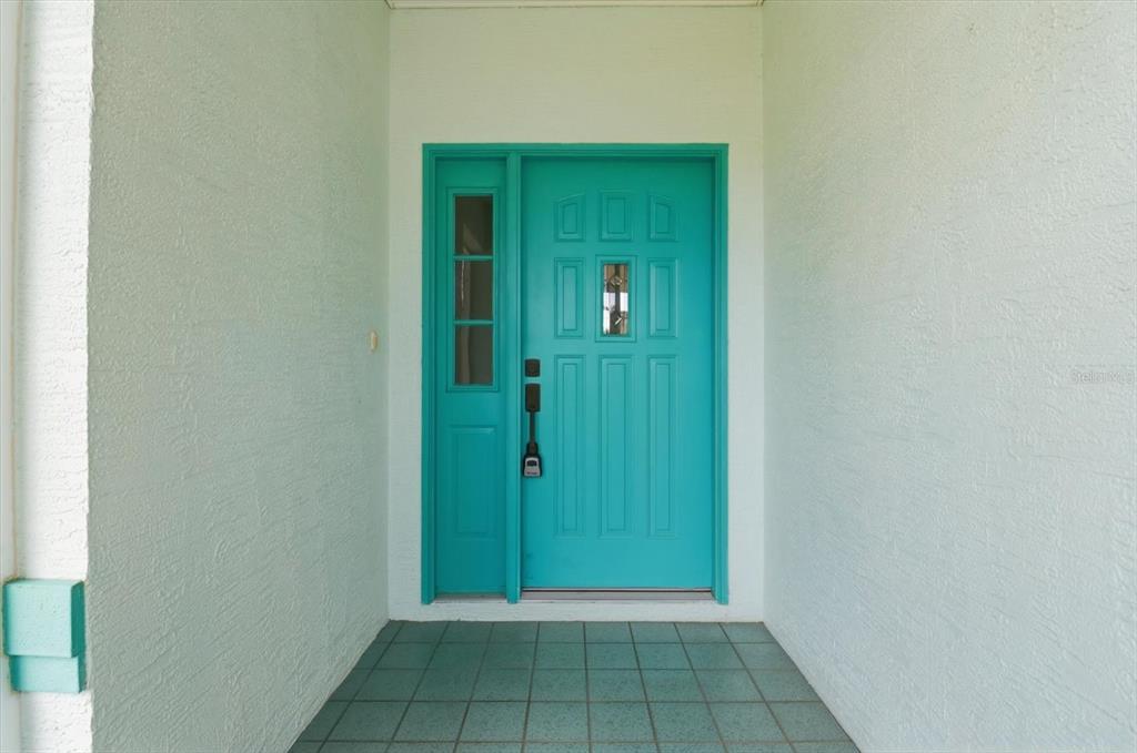 A turquoise front door with a side window sits under a covered entryway — 1209 N TIMUCUAN TRAIL, INVERNESS, FL
