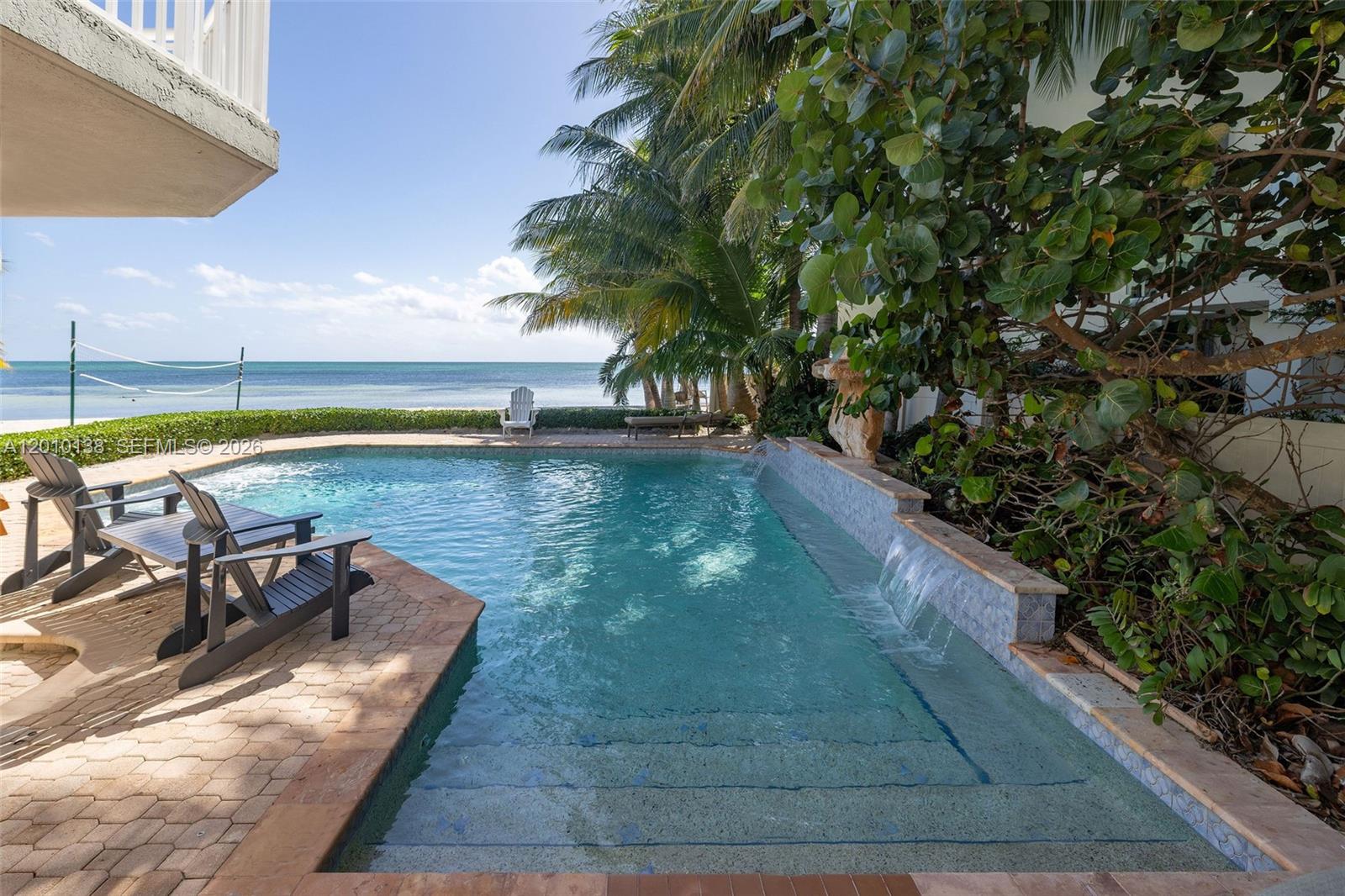 An outdoor swimming pool with a waterfall feature overlooks the ocean from a paved patio — 74049 Overseas, Islamorada FL 33036, ISLAMORADA, FL