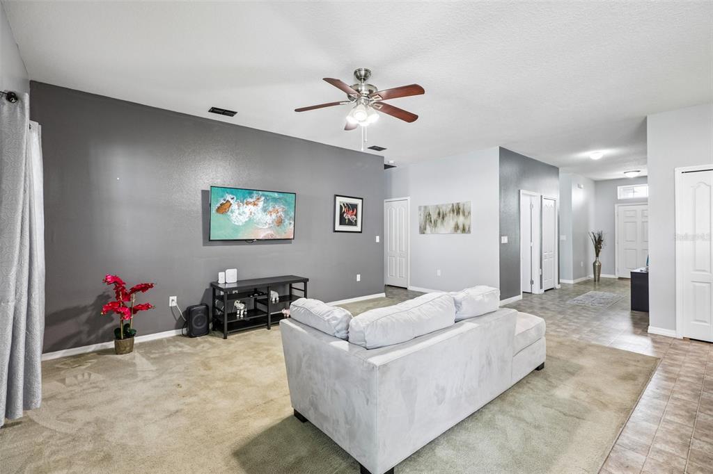 A living room features gray walls, a white sofa, carpeted flooring, and a ceiling fan — 954 REVERE AVENUE, HAINES CITY, FL