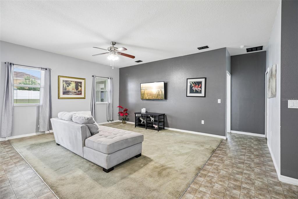 A living room features a grey accent wall, a sectional sofa, and beige carpeting — 954 REVERE AVENUE, HAINES CITY, FL