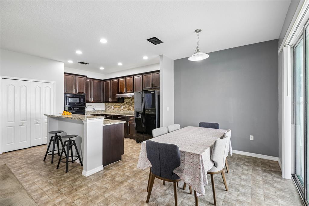 A kitchen with dark wood cabinets and a dining area with a table and chairs — 954 REVERE AVENUE, HAINES CITY, FL