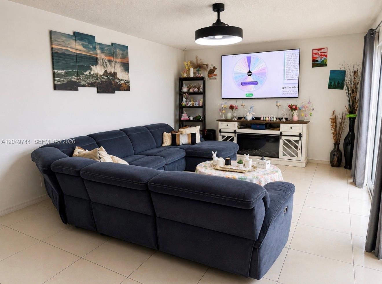A living room features a large blue sectional sofa, a fireplace console, and wall art — 4804 Waterview Cir, Palm Springs FL 33461, PALM SPRINGS, FL