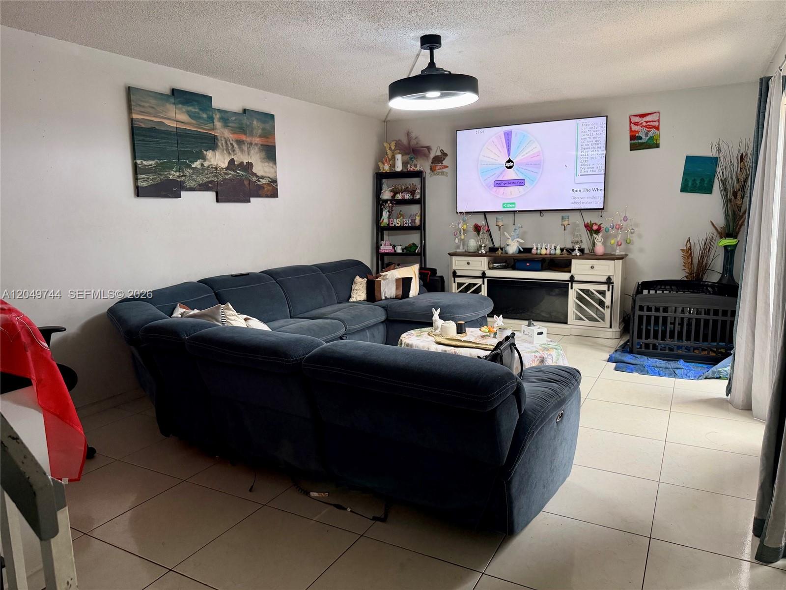 A living room features a blue sectional sofa, a television, and tile flooring — 4804 Waterview Cir, Palm Springs FL 33461, PALM SPRINGS, FL