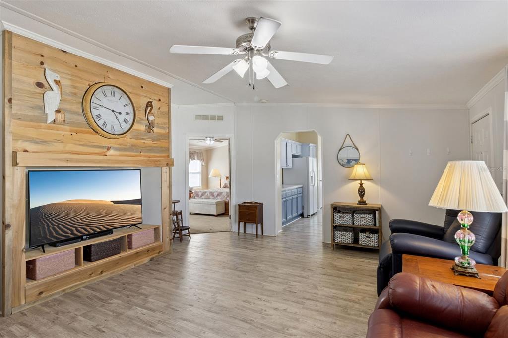 A living room features a wood-paneled accent wall with a television and a ceiling fan — 3100 MARK LANE, LAKE WALES, FL