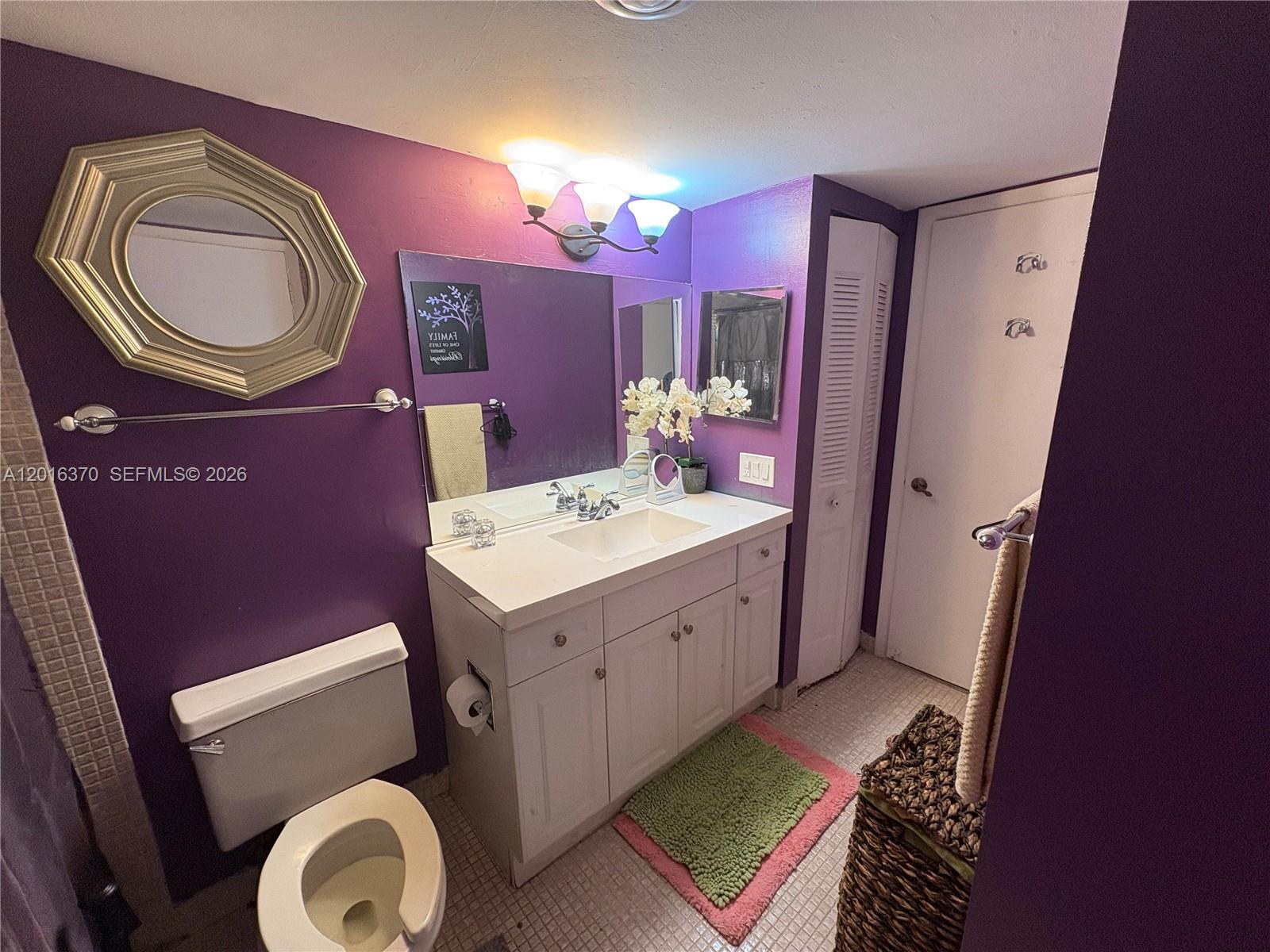 A bathroom features purple walls, a white vanity with a sink, and a toilet — 4152 Inverrary Dr # 303, Lauderhill FL 33319, LAUDERHILL, FL