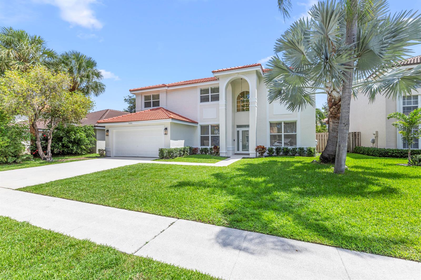 A two-story house with a white stucco exterior, red tile roof, and a palm tree — 7686 Cedar Hurst Court, Lake Worth FL 33467, LAKE WORTH, FL