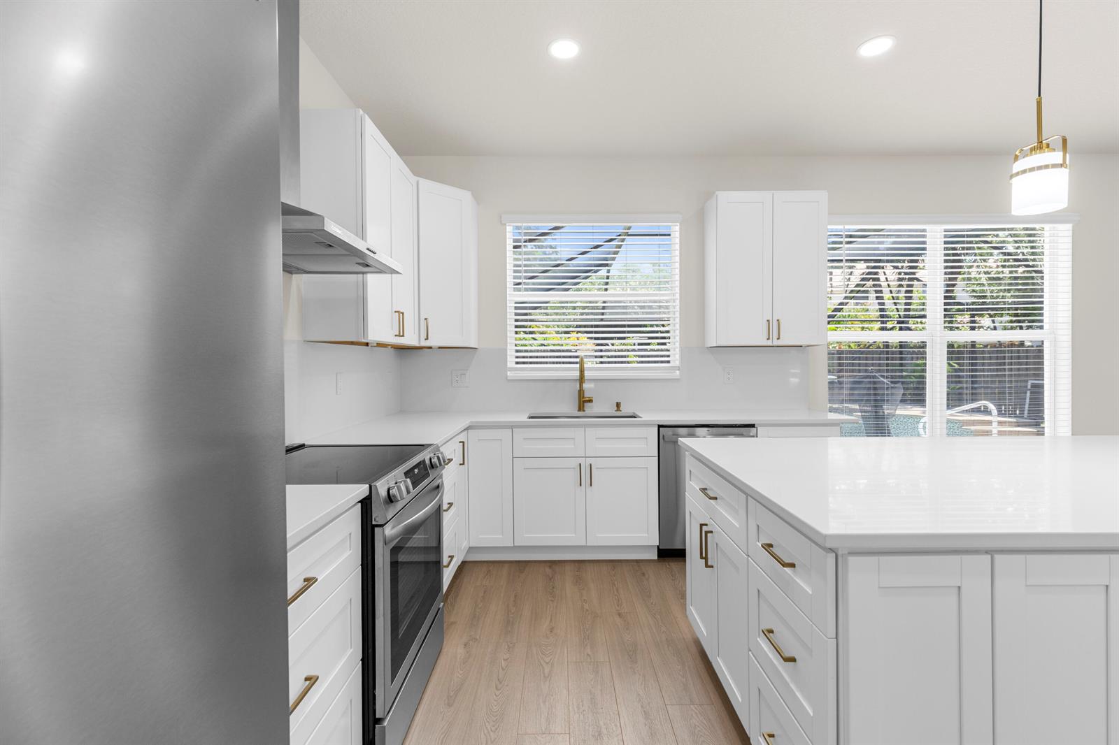 A modern kitchen features white cabinets, gold hardware, stainless steel appliances, and a large island — 7686 Cedar Hurst Court, Lake Worth FL 33467, LAKE WORTH, FL
