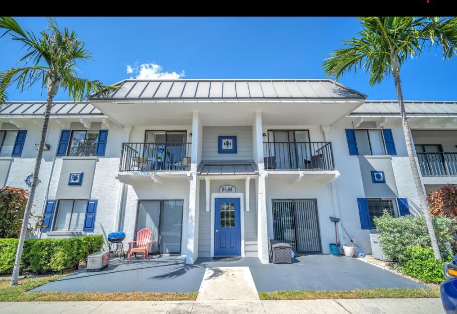 A two-story apartment building exterior featuring a blue front door, balconies, and palm trees — 3100 S Dixie Highway, Boca Raton FL 33432, BOCA RATON, FL