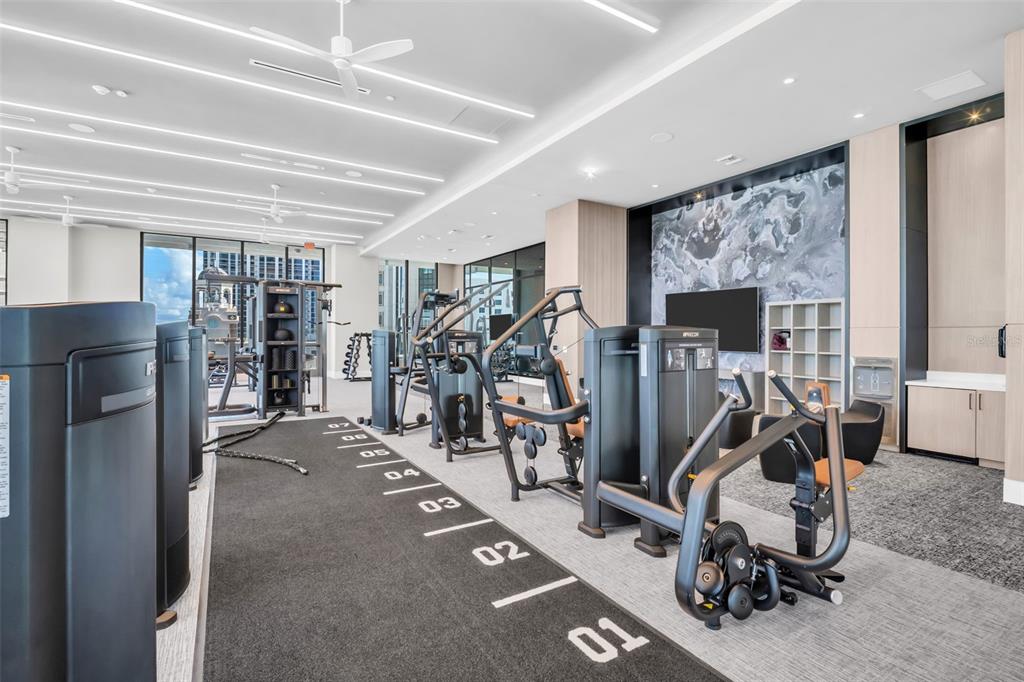 A modern gym features numbered floor markings, various exercise machines, and a large marble wall — 275 1ST AVENUE S UNIT 2807, ST PETERSBURG, FL