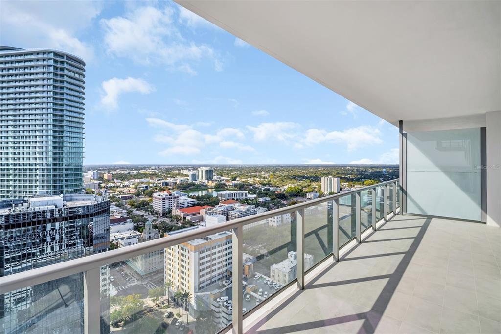 A high-rise balcony with a glass railing overlooks a city skyline and a nearby lake — 275 1ST AVENUE S UNIT 2807, ST PETERSBURG, FL