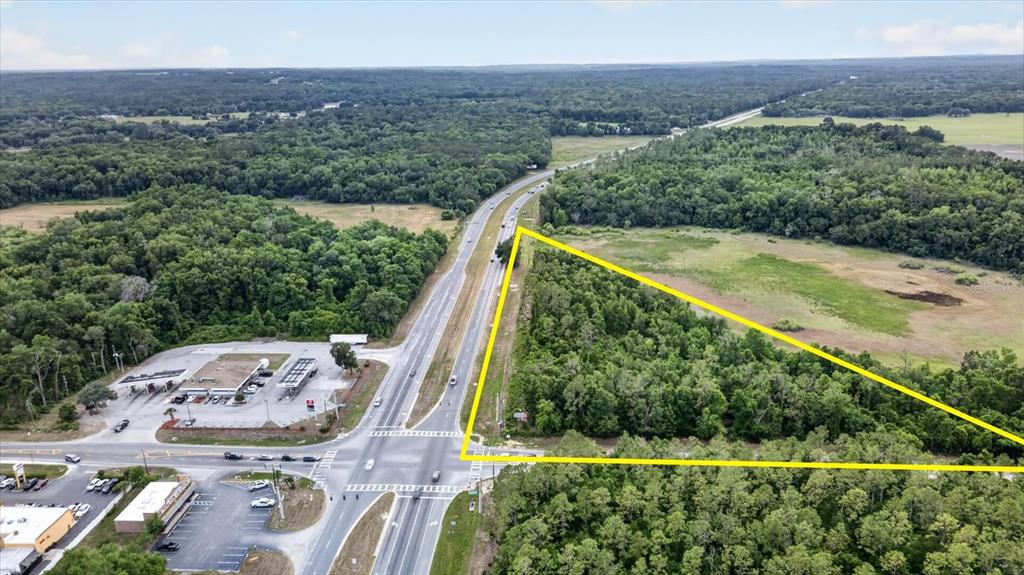 An aerial view shows a triangular plot of land bordered by a highway and forest — MONDON HILL, BROOKSVILLE, FL