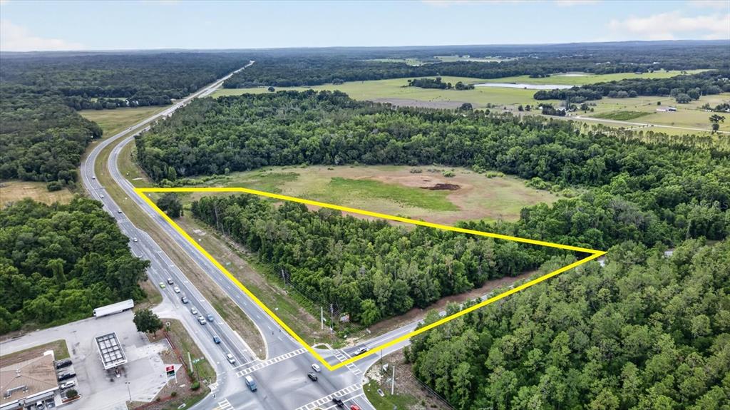An aerial view shows a triangular plot of land outlined in yellow near a highway — MONDON HILL, BROOKSVILLE, FL