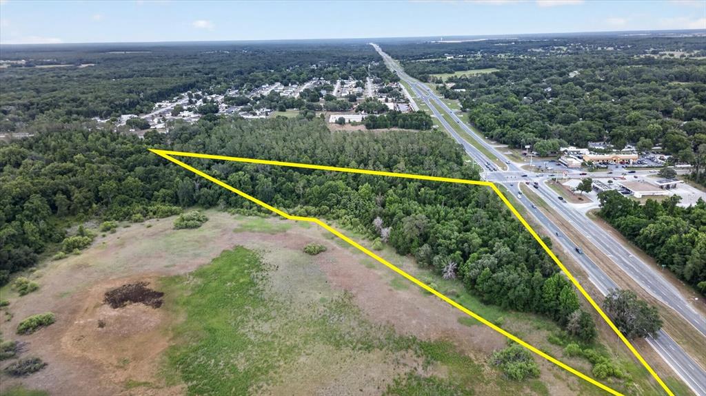 An aerial view shows a wooded, triangular plot of land adjacent to a highway — MONDON HILL, BROOKSVILLE, FL