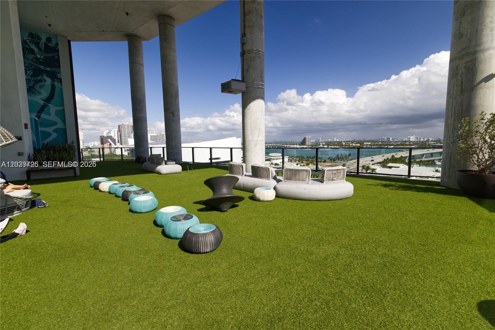 An outdoor rooftop terrace features artificial turf, modern lounge seating, and panoramic city and water views — 398 NE 5th St # 2112, Miami FL 33132, MIAMI, FL