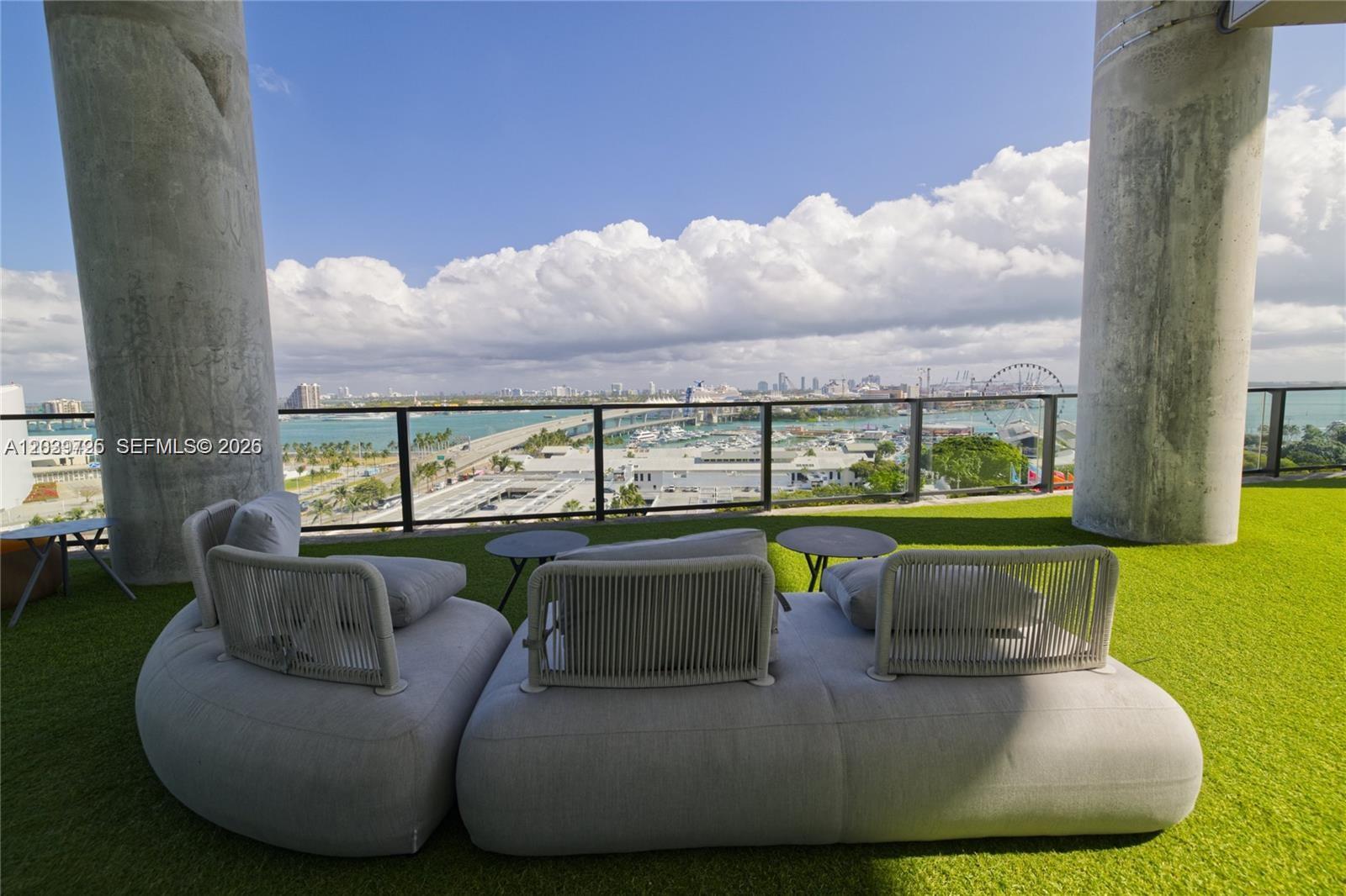 A balcony with artificial turf, modern outdoor seating, and a view of the city skyline — 398 NE 5th St # 2112, Miami FL 33132, MIAMI, FL